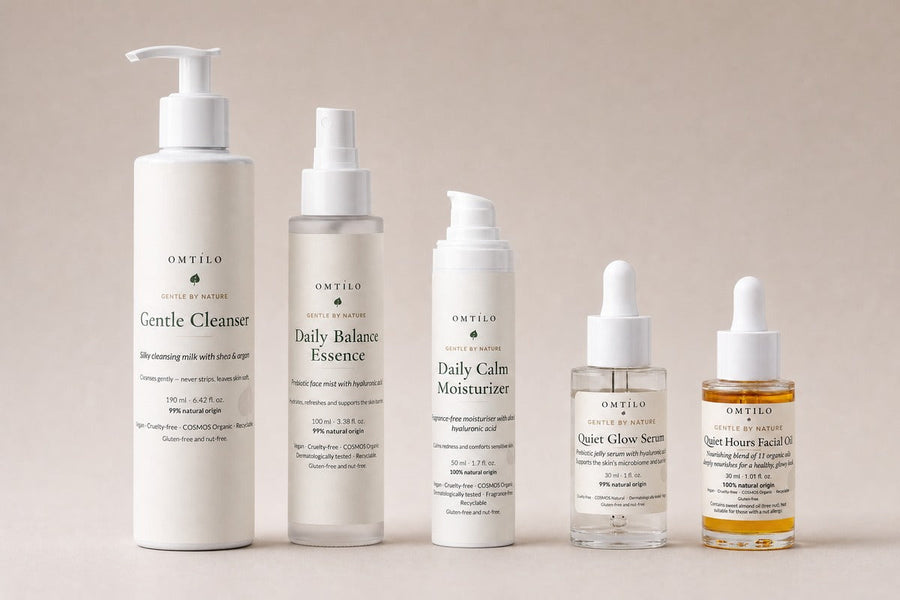 The five OMTILO skincare products grouped together as a set on a warm beige background